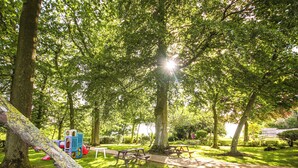 En park med picnicborde og et legeområde.