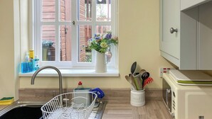 A kitchen with a sink, dish rack, window with flowers, and a microwave. - 5 steps to entrance. (Burythorpe near Malton)