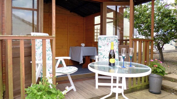 A wooden cabin with a glass table and two chairs, a bottle of wine, and a potted plant. - 5 steps to entrance. (Burythorpe near Malton)