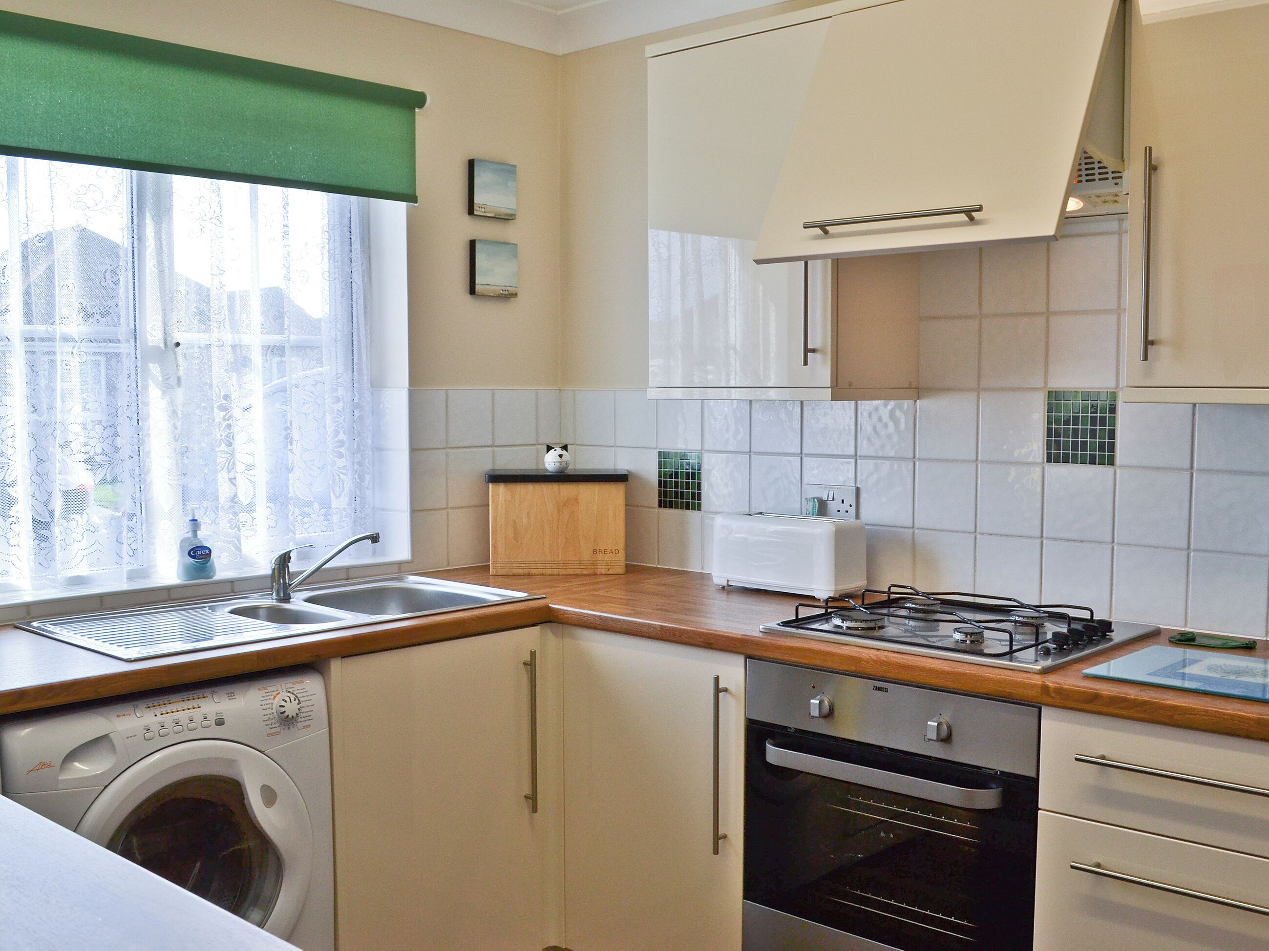 A compact kitchen with a washing machine, a toaster, and a stove.