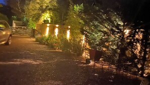 Ein gepflasterter Weg führt zu einem verschlossenen Eingang mit Holzzaun und Topfpflanzen.