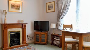 Una sala de estar con chimenea, televisión, muebles de madera y dos cuadros en la pared.