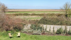 Een tuin met twee stoelen, een houten omheining en uitzicht op een vlak landschap.