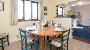 Een eetgedeelte met een ronde houten tafel, blauwe stoelen en een hangende lamp.