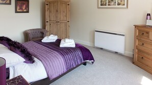 A bedroom with a bed, a wardrobe, a radiator, and a dresser. - Blaeberry Cottage - 28061 (Near Lockerbie)