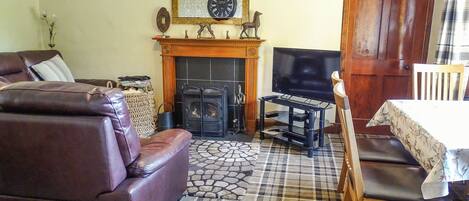 Ein Wohnzimmer mit Kamin, Fernseher, einer Couch und einem Essbereich.