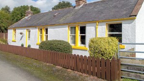 A white house with yellow trim and a brown picket fence. - Blaeberry Cottage - 28061 (Near Lockerbie)