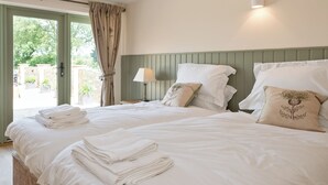 Een slaapkamer met twee bedden, een raam met gordijnen, een bedlampje en uitzicht op buiten.