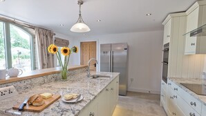 Een moderne keuken met een marmeren aanrecht, roestvrijstalen apparatuur en een vaas met zonnebloemen.