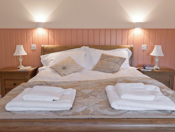 A neatly made bed with pillows, two bedside lamps, and a stack of folded towels. - 5 bedroom accommodation in East Barkwith, near Market Rasen (East Barkwith, near Market Rasen)