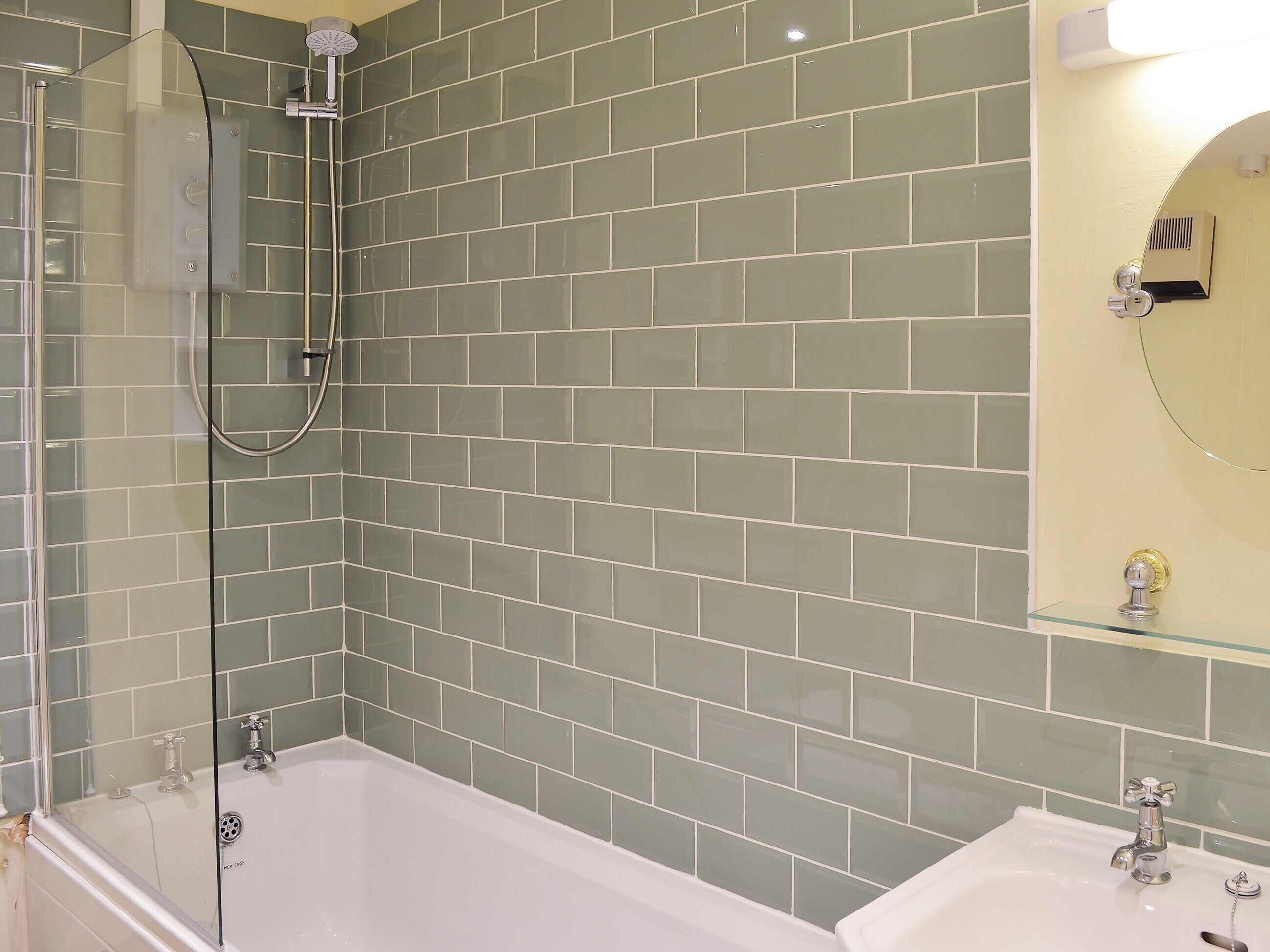 A bathroom with a glass-enclosed shower, a white bathtub, and a sink with a mirror above it.
