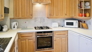 A kitchen with wooden cabinets, a gas stove, a microwave, and a dishwasher.