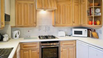 Une cuisine avec des meubles en bois, une cuisinière à gaz, un four à micro-ondes et un lave-vaisselle.