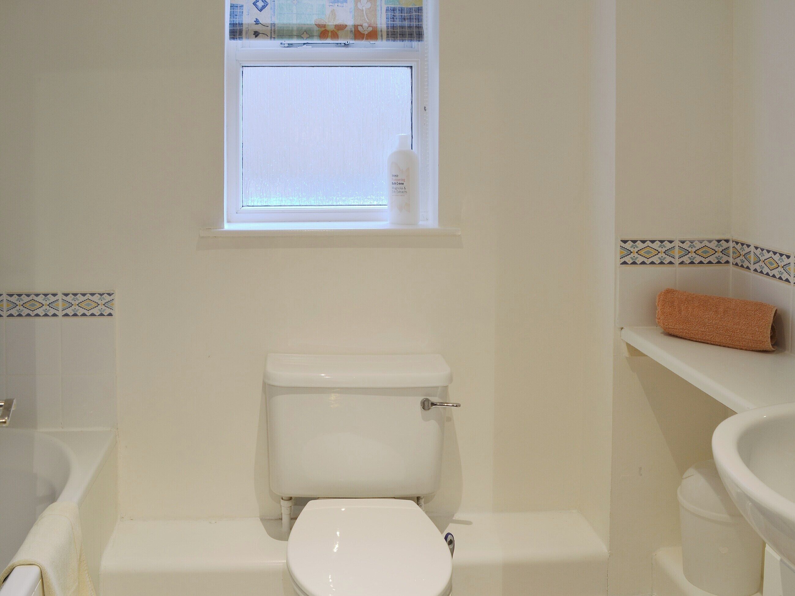 Une salle de bain avec des toilettes, une fenêtre et un lavabo.