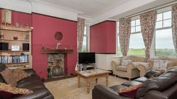 A living room with a fireplace, leather sofas, a coffee table, and a television.