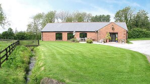 A brick building with a sloped roof, a paved driveway, and a well-maintained lawn. - 6 bedroom accommodation in Arkleby, near Cockermouth (Arkleby, near Cockermouth)