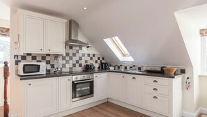 Eine moderne Küche mit weißen Schränken, einer Mikrowelle, einem Backofen, einem Spülbecken und einem Oberlicht.
