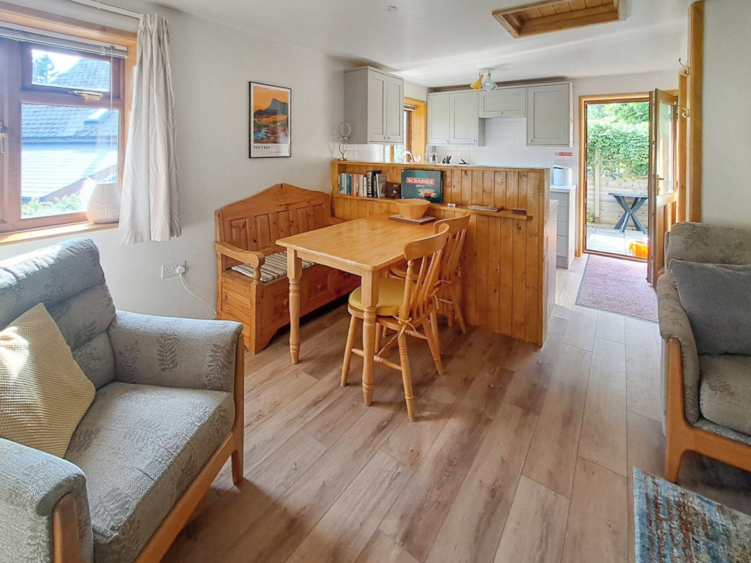 Un espacio habitable acogedor y de concepto abierto, con una mesa y sillas de madera, un sofá y una zona de cocina.