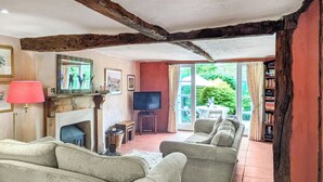 A cozy living room with a fireplace, a television, and a sofa. - 2 bedroom accommodation in Halesworth (Halesworth)