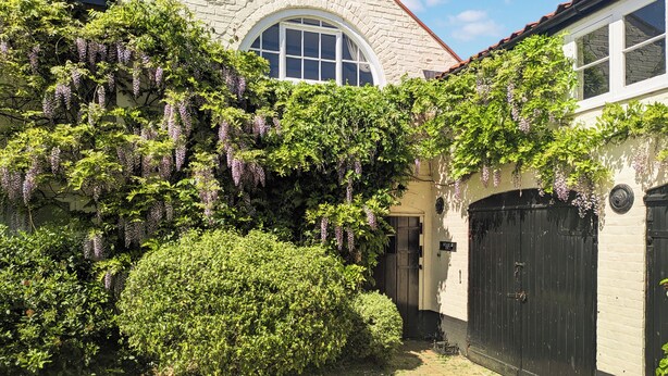 A building with a stone facade, a large arched window, and a black gate. - 2 bedroom accommodation in Halesworth (Halesworth)