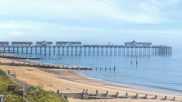 A pier extending into calm waters with beach access and a clear sky.