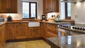A kitchen with wooden cabinets, a granite countertop, a stainless steel range hood, and a window providing natural light.