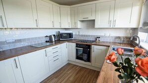 A modern kitchen with white cabinets, a microwave, a kettle, and a sink. - 3 bedroom accommodation in Padstow (Padstow)