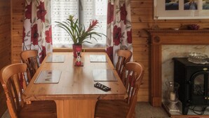 Una mesa de comedor de madera con dos sillas, una planta en maceta y un control remoto sobre la mesa.