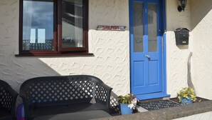 A building with a blue door, a window with a dark frame, and a sign that reads "SAILFISH". - 3 bedroom accommodation in Benllech (Benllech)