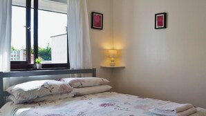 A neatly made bed with floral bedding, a bedside lamp, and two framed pictures on the wall. - 3 bedroom accommodation in Benllech (Benllech)