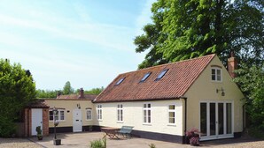 Une maison à deux étages, avec un toit en tuiles, un porche à l’avant et une allée gravillonnée.