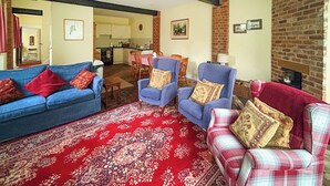 Un salon avec un tapis rouge à motifs, des canapés bleus et à carreaux, et une cheminée en briques.