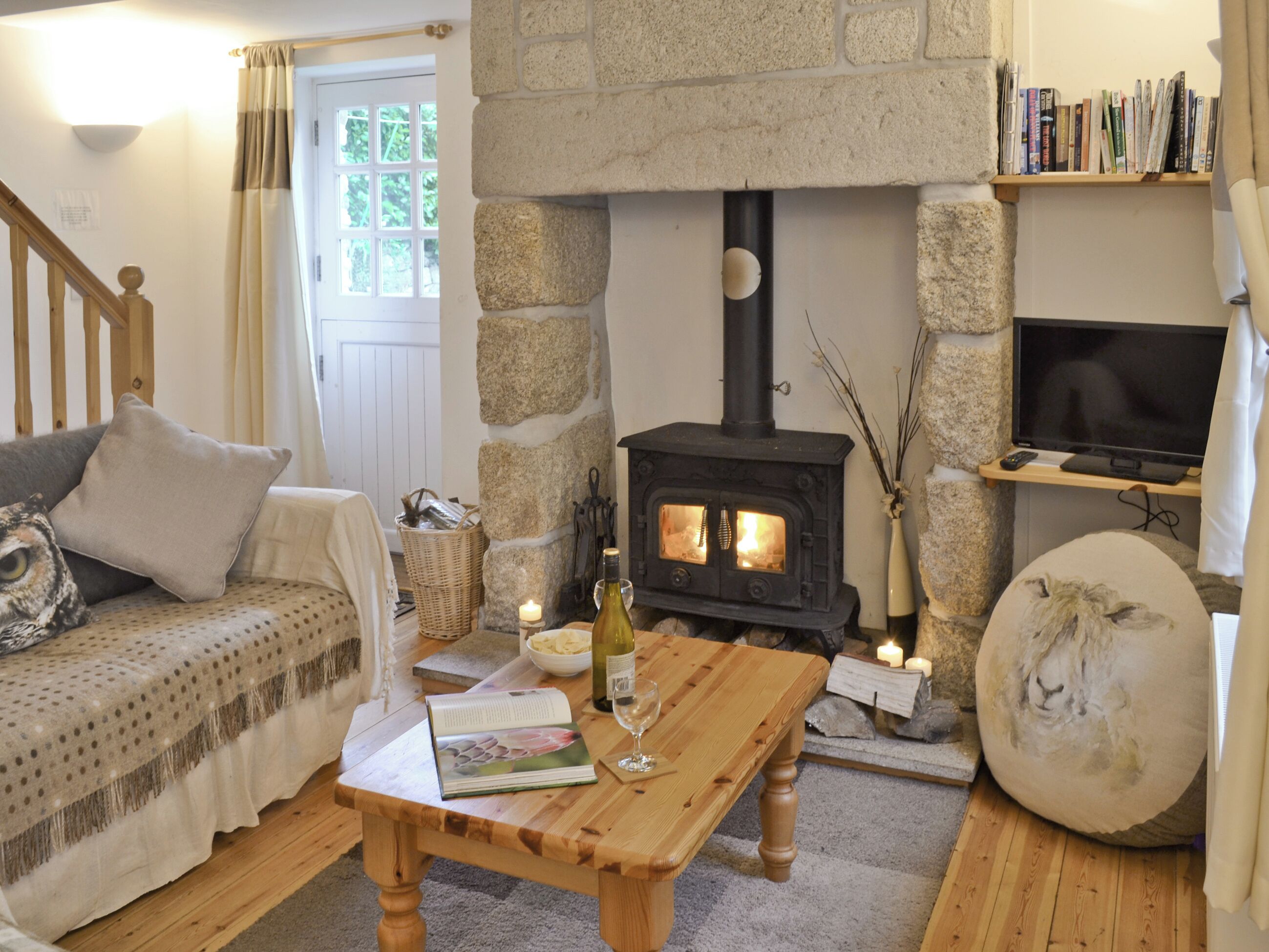A cozy living room with a stone fireplace, a wooden coffee table, a sofa, and a television.