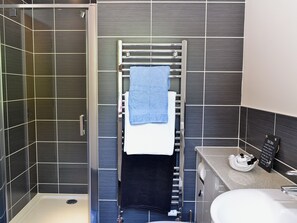 Un baño moderno con ducha, toallero con toallas, inodoro y lavabo.