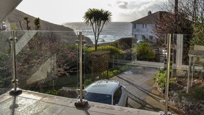 A coastal view from a balcony with a car parked below, overlooking the sea and a residential area. - The lounge is a room with a view. (Heybrook Bay, near Plymouth)