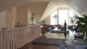 A dining area with a wooden table, chairs, and a view of the living room. - The lounge is a room with a view. (Heybrook Bay, near Plymouth)