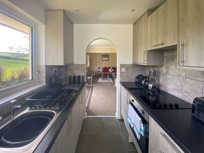 A modern kitchen with a large window, stainless steel appliances, and a view of the outdoors.