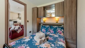 Un dormitorio con colcha estampada, un sofá rojo, armarios de madera y un espejo sobre la cama.