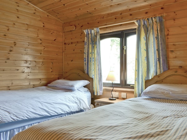 A cabin-style room with two single beds, a window with curtains, and a bedside lamp. - 3 bedroom accommodation in Keswick (Keswick)