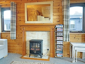 A cozy room with a fireplace, wooden walls, a bookshelf, and a window. - 3 bedroom accommodation in Keswick (Keswick)