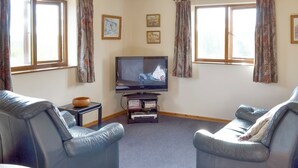 A living room with two leather sofas, a television on a stand, and a small table with a bowl. - 1 bedroom accommodation in Dartington, Totnes (Dartington, Totnes)