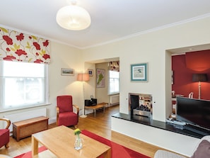 A living room with a fireplace, a television, a red chair, and a wooden coffee table.