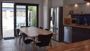 A modern kitchen with a large dining table, built-in appliances, and a sliding glass door leading to a patio. - 3 bedroom accommodation in Yarmouth (Yarmouth)