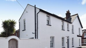 A two-story white building with a brick chimney, a wooden door, and multiple windows. - 3 bedroom accommodation in Yarmouth (Yarmouth)