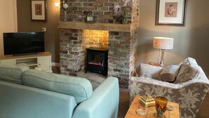 A living room with a brick fireplace, a television, a sofa, and a patterned armchair. - All on the Ground Floor: 
Open plan living space. (Lockton, near Pickering)