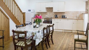 A kitchen with wooden cabinets, a dining table with chairs, a microwave, and a coffee maker.