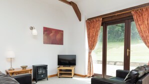 Ein Wohnzimmer mit Ledersofa, Fernseher, einem Holztisch mit Lampe und einem Gemälde an der Wand.