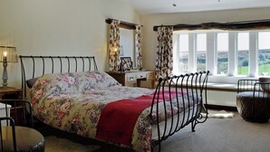 Ein Schlafzimmer mit einem Bett, einem Schreibtisch, einem Stuhl, einem Heizkörper und einem Fenster mit Blick.