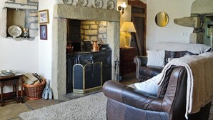 Ein gemütliches Wohnzimmer mit Kamin aus Stein, Ledersofa und rustikalem Dekor.