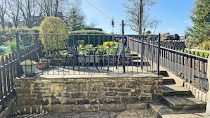 A stone staircase leading to a gated area with metal railings and potted plants. - 20 steps to entrance with handrail. (Burnsall near Grassington)